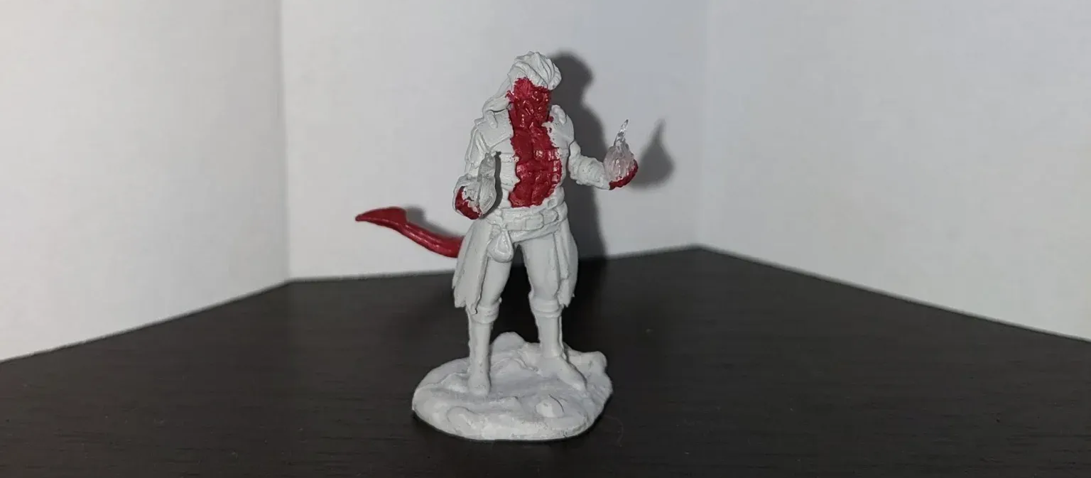 Miniature figure of a humanoid with red markings on white clothing, holding a knife.