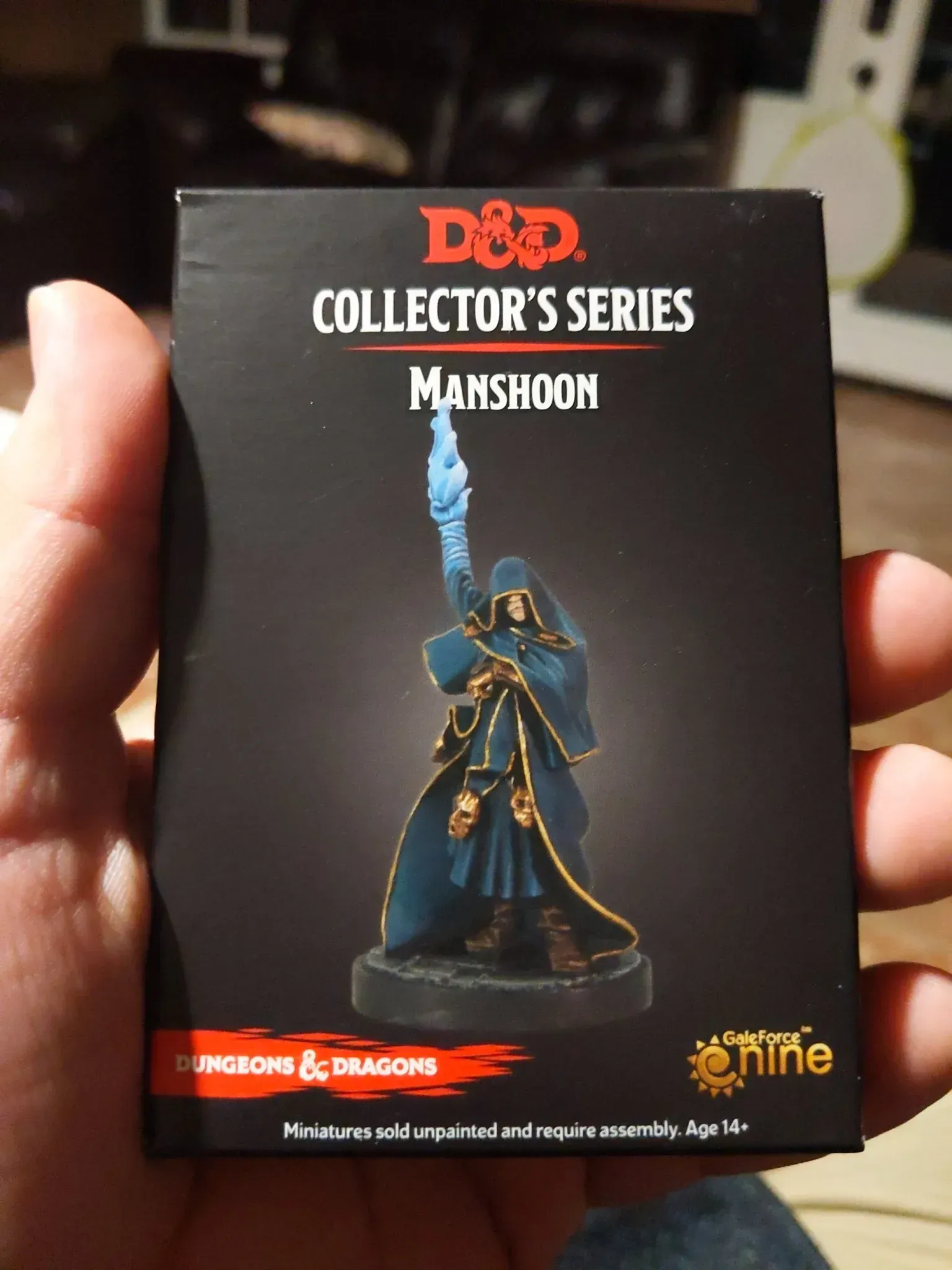 Hand holding a D&D Collector's Series Mamshoon miniature box. The figure is blue-robed with a blue flame.