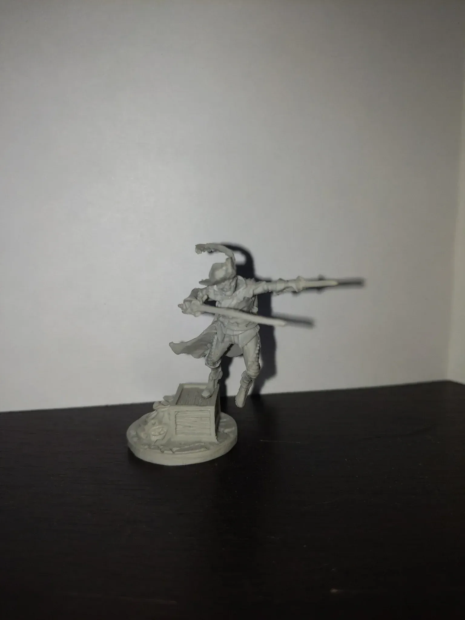 Miniature figure of a character in a hat, aiming a rifle, standing on a stone structure.
