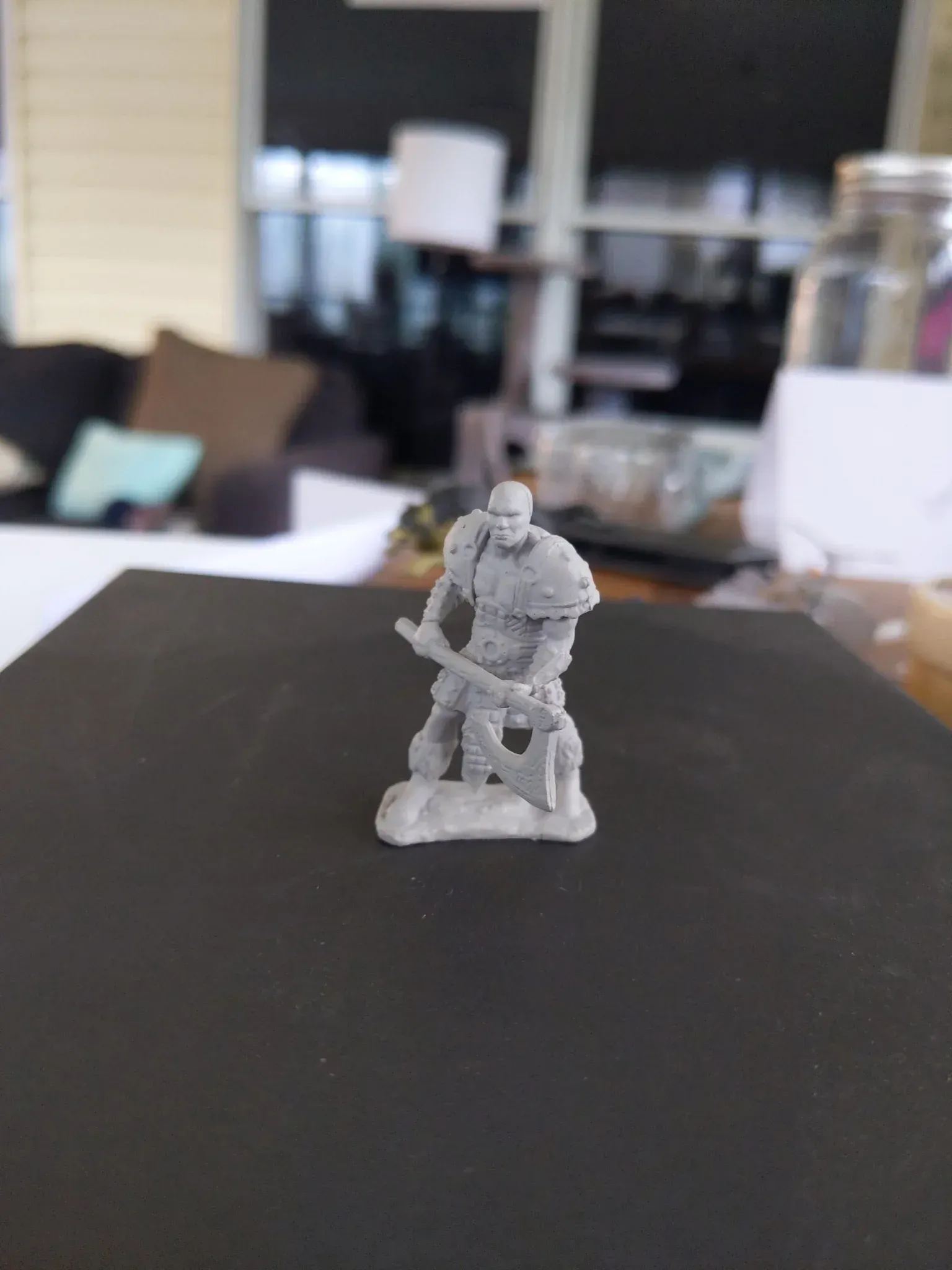 Miniature figure of a warrior, gray plastic, holding an axe.