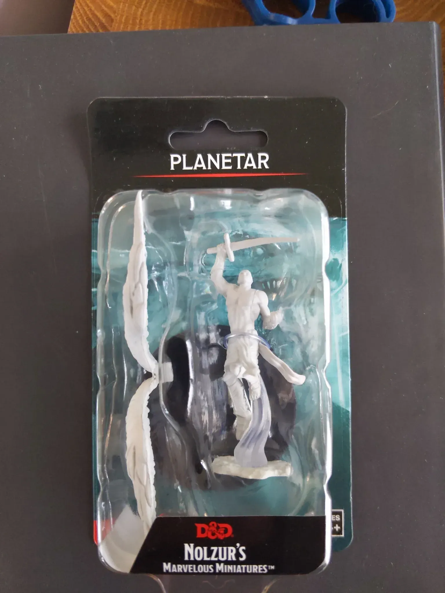 Planetar miniature figure in blister packaging. White humanoid figure with sword and wings.