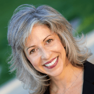 A woman with gray hair is smiling for the camera.