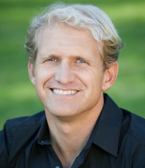 A man in a black shirt is smiling for the camera