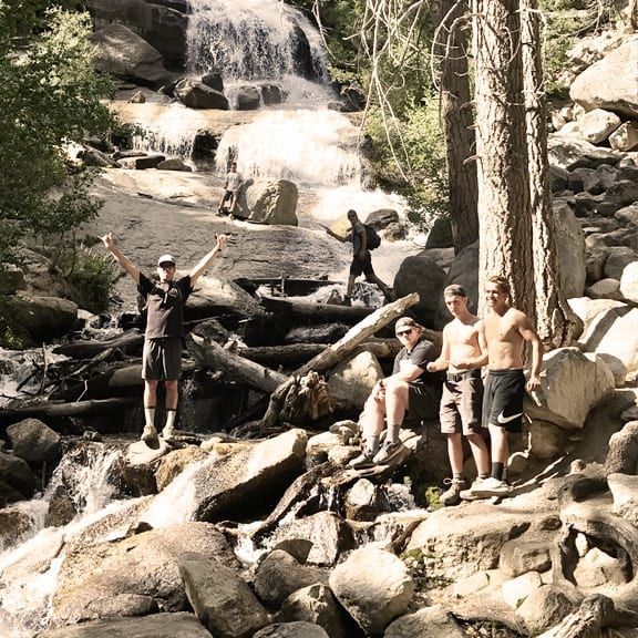 A group of men are posing for a picture in front of a waterfall