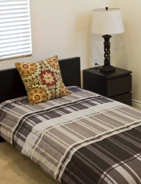 A bed with a striped comforter and a pillow on it