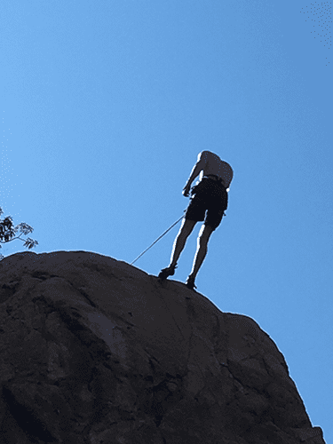 A person is climbing a rock with a rope
