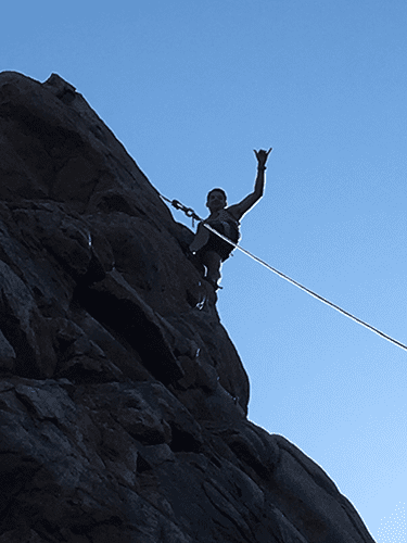 A person is hanging from a rope on a rocky cliff