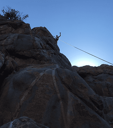 A person is hanging from a rope on a rocky cliff