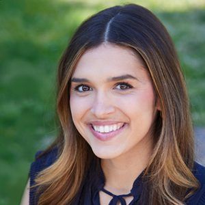 A woman in a blue shirt is smiling for the camera.