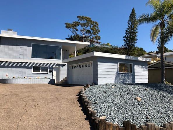 A house with a garage and a palm tree in the background