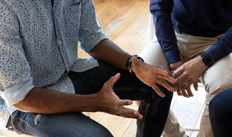 A group of people are sitting in a circle talking to each other.