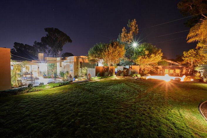 A large lawn with a house in the background at night.