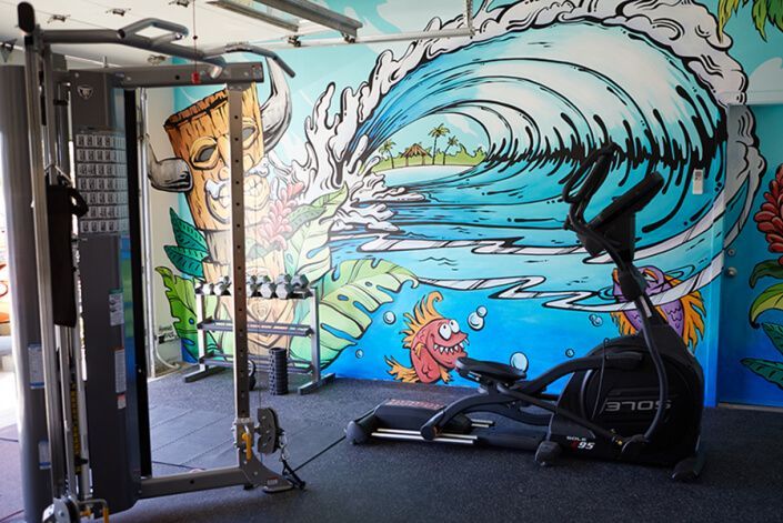 A gym with a mural on the wall and a treadmill