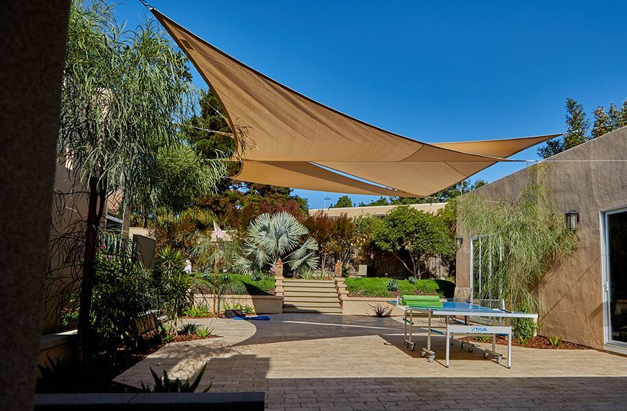 A patio with a table and chairs under a shade sail.