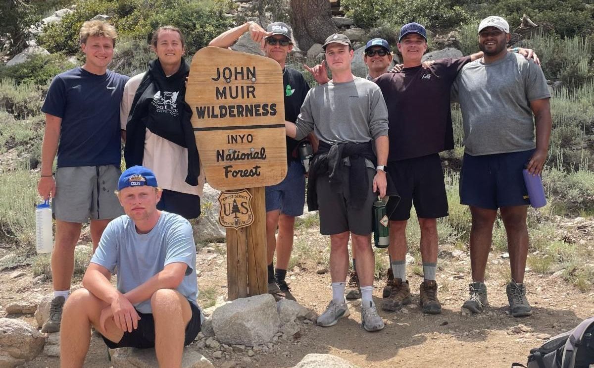 Group of hikers at the John Muir Wilderness sign. Sunny day, people smiling and posing.