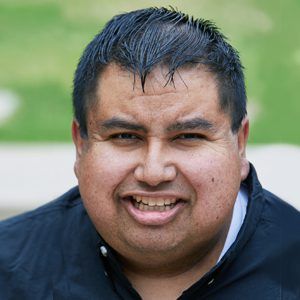 A man in a black jacket is smiling for the camera.