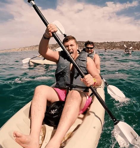 A man in a life jacket is rowing a kayak in the ocean.