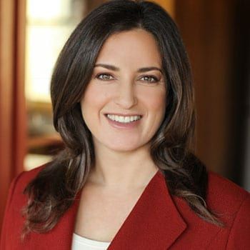 A woman in a red jacket is smiling for the camera.