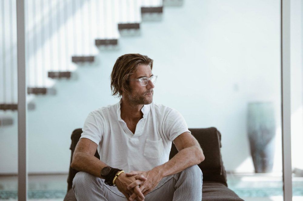 A man is sitting on a couch in front of a staircase.