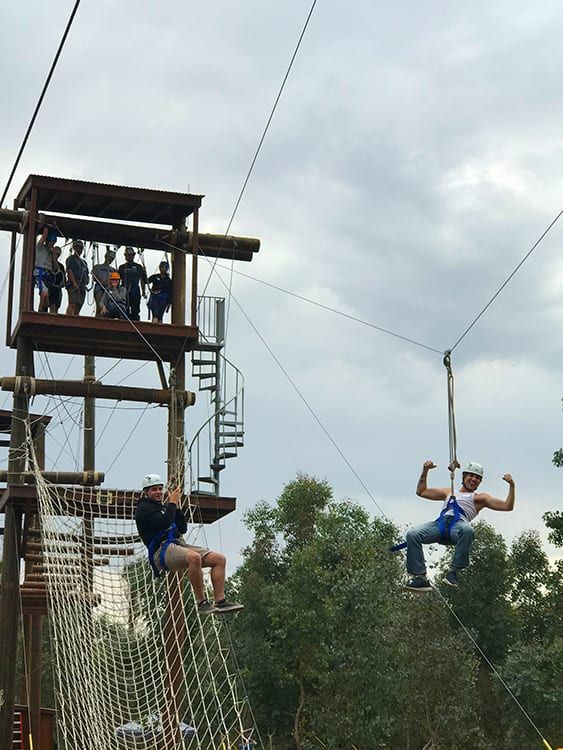 A man is riding a zip line in a park