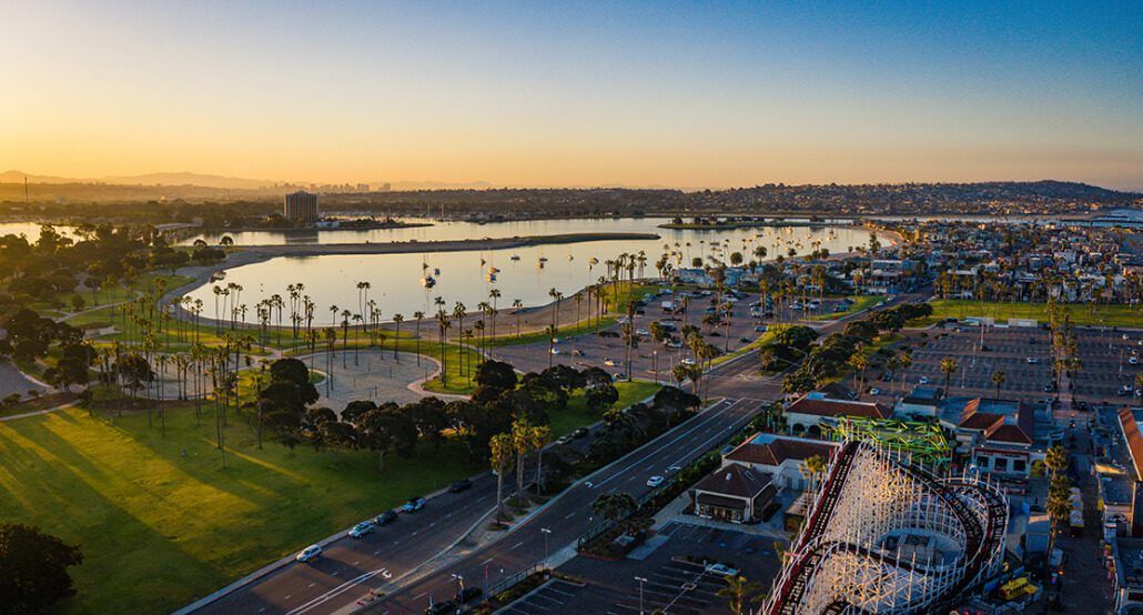 An aerial view of a city with a lake and a park at sunset.