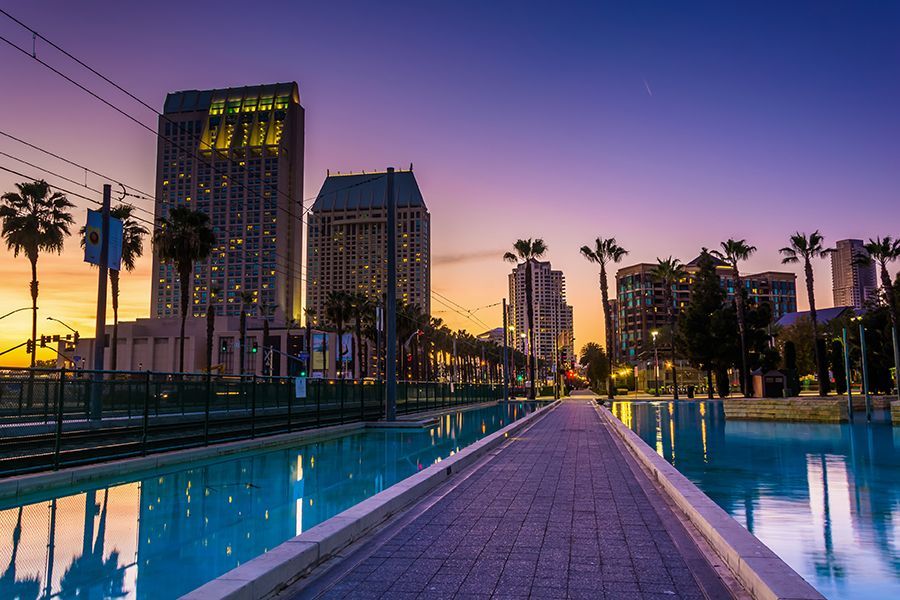 A brick walkway leading to a city at sunset.