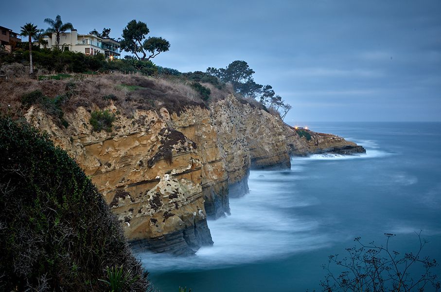 A house is sitting on top of a cliff overlooking the ocean.