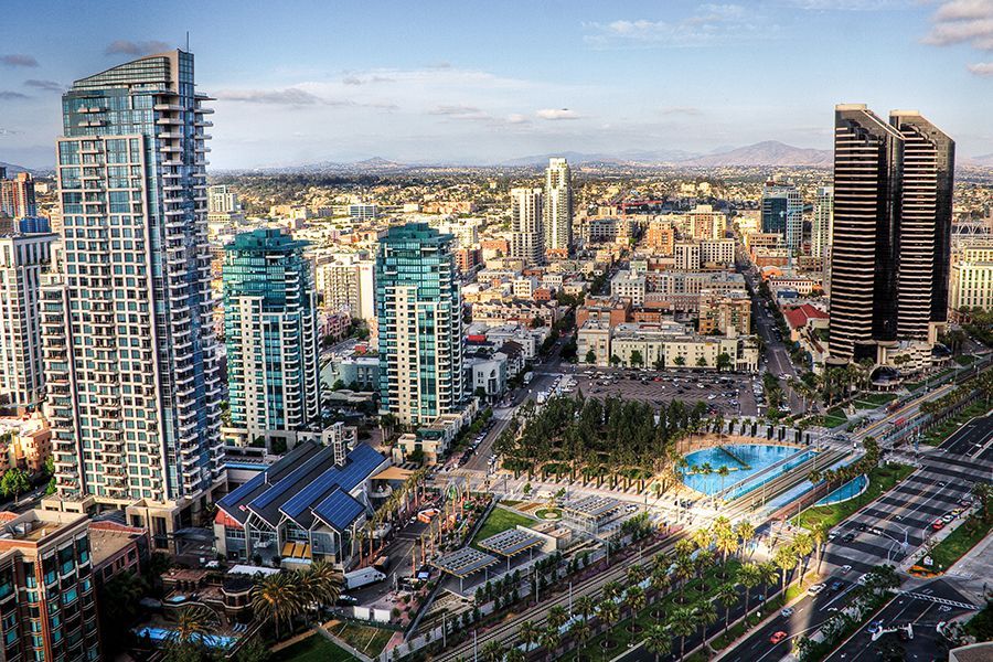 An aerial view of a city with lots of tall buildings and a pool in the middle of the city.