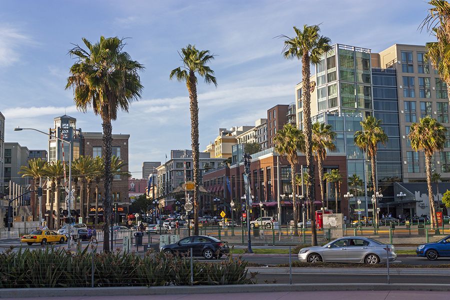 A city street with palm trees and cars driving down it