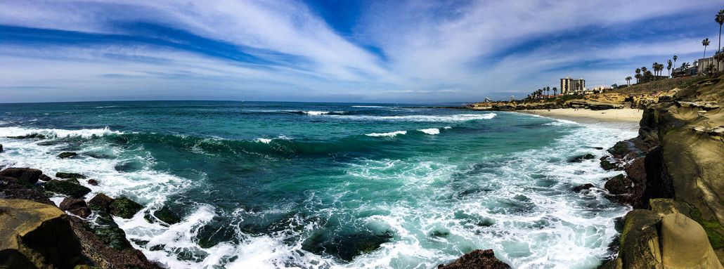 A view of the ocean from a rocky cliff on a sunny day.