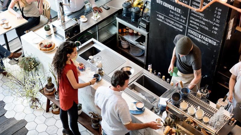 A group of people are standing at a counter in a restaurant.