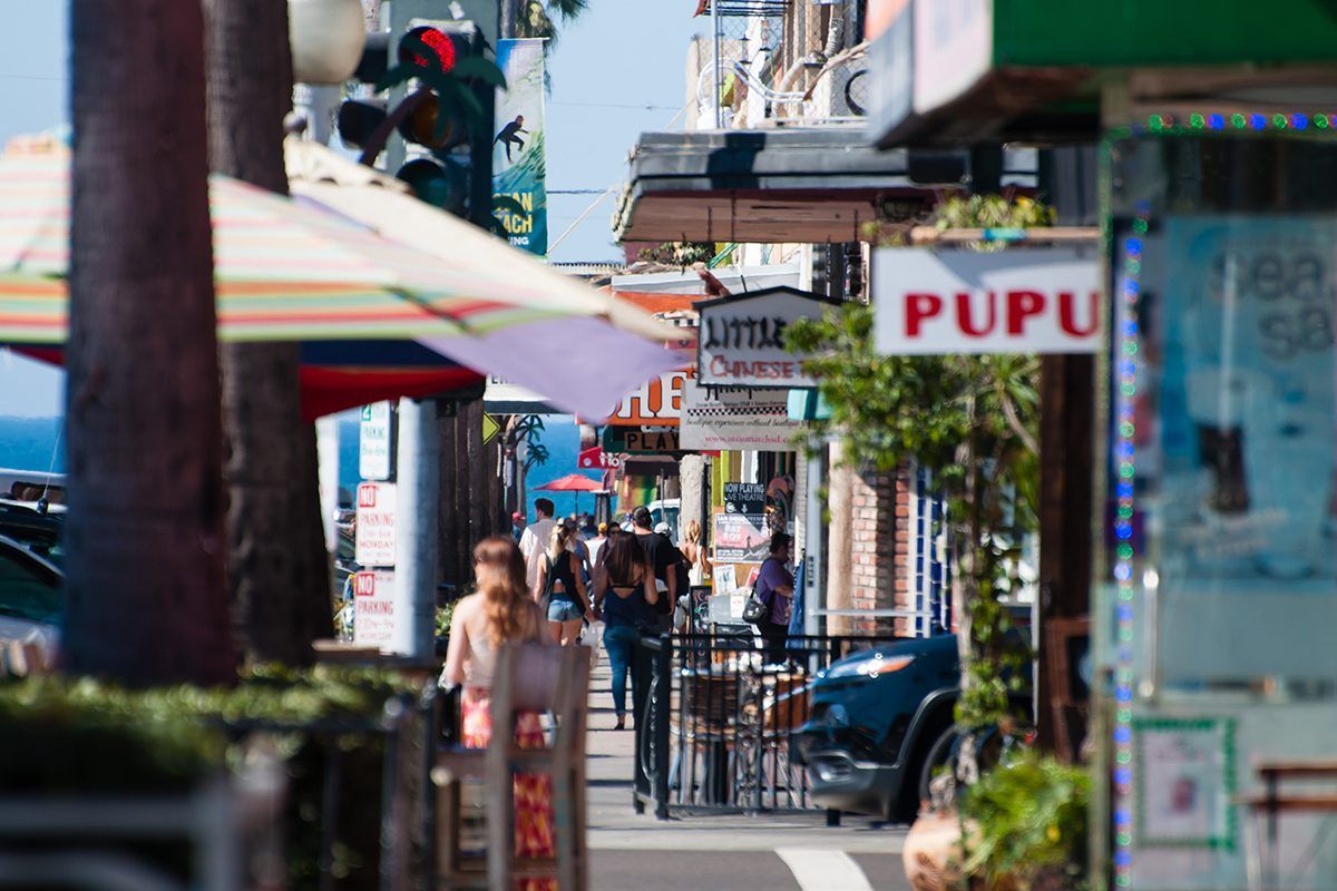 A group of people are walking down a sidewalk in front of a pupu restaurant.