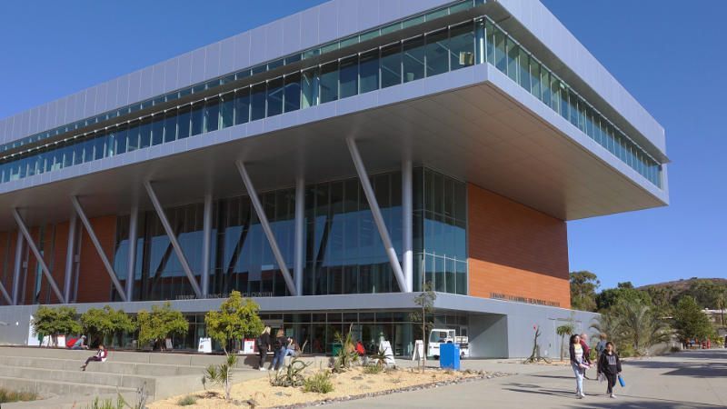 A large building with a lot of windows and people walking in front of it