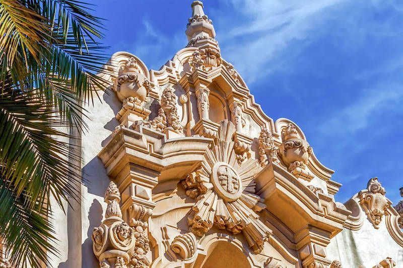 A building with a palm tree in the foreground and a blue sky in the background.