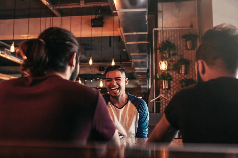 A group of men are sitting at a table in a restaurant talking to each other.