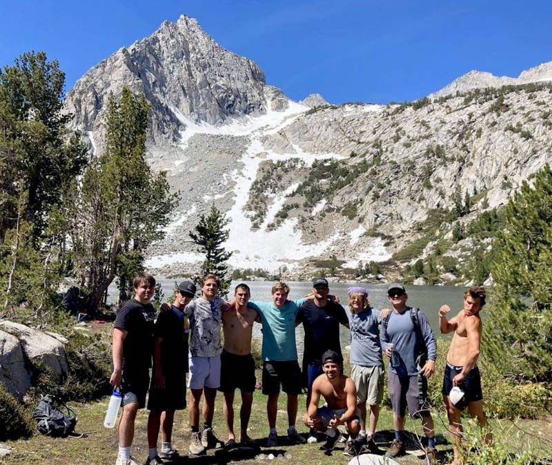 A group of people are posing for a picture in front of a mountain.