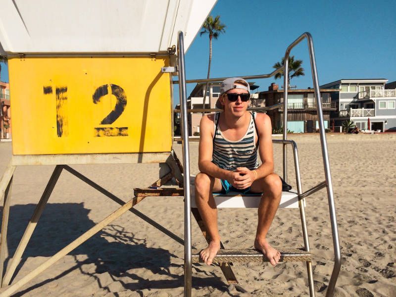 A man sits in a lifeguard chair on the beach