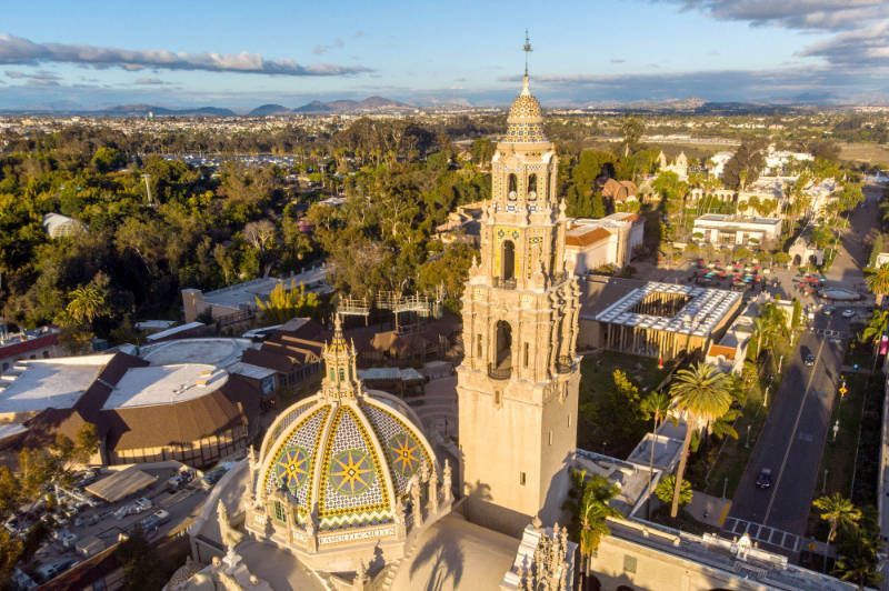 An aerial view of a church with a clock tower in the middle of a city.