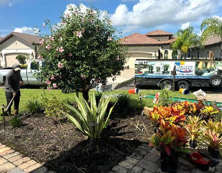 A man is working in a garden with a truck in the background.