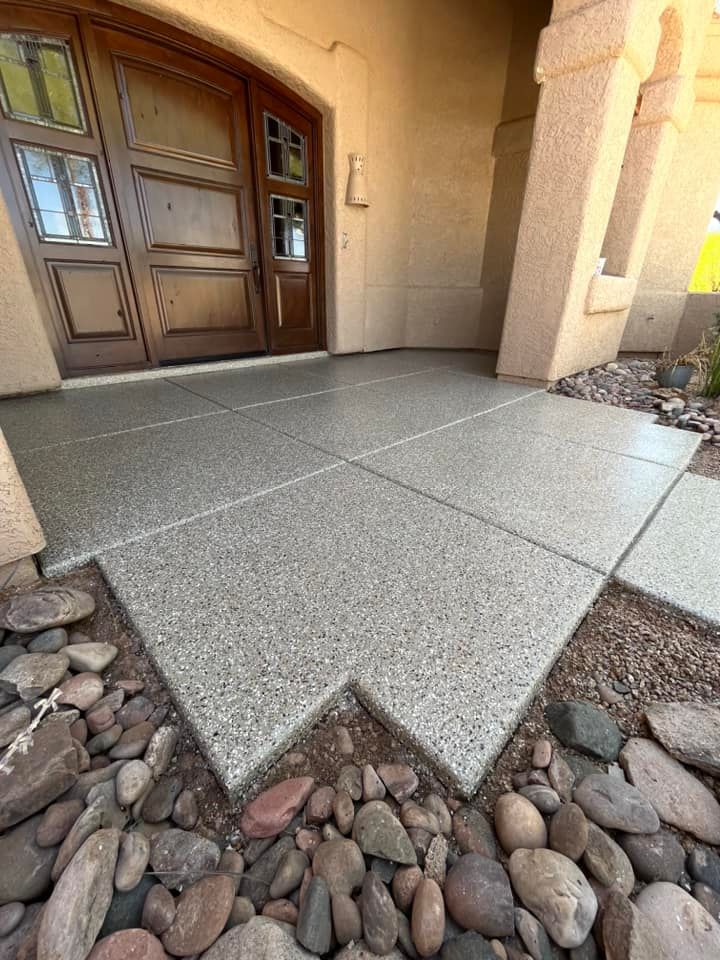A concrete walkway with rocks in the foreground and a wooden door in the background.