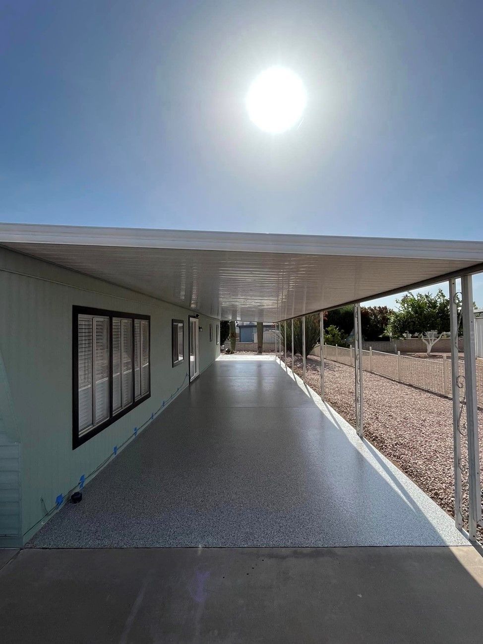 A long walkway leading to a house with the sun shining through the windows