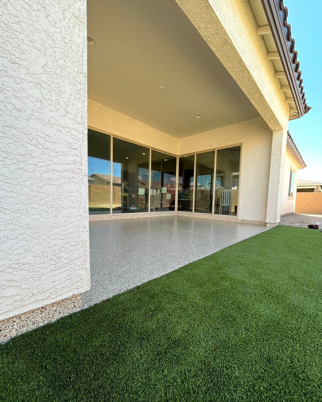 A patio with a lot of windows and a lawn in front of it.