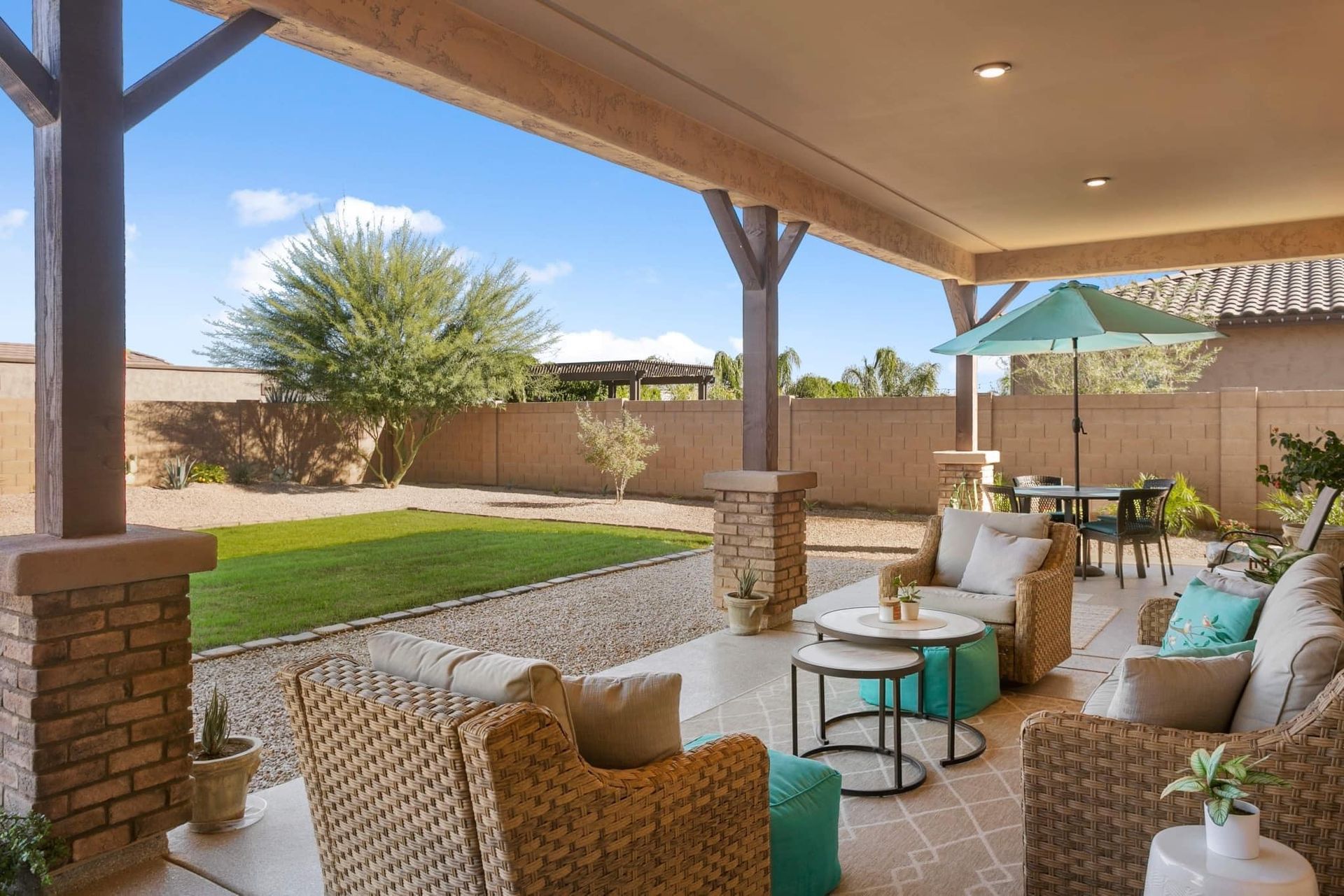 A patio with wicker furniture and a green umbrella