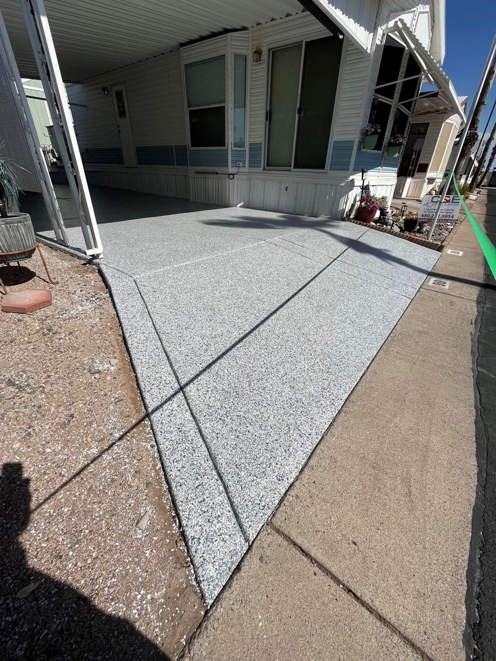 A person is standing on a sidewalk in front of a mobile home.