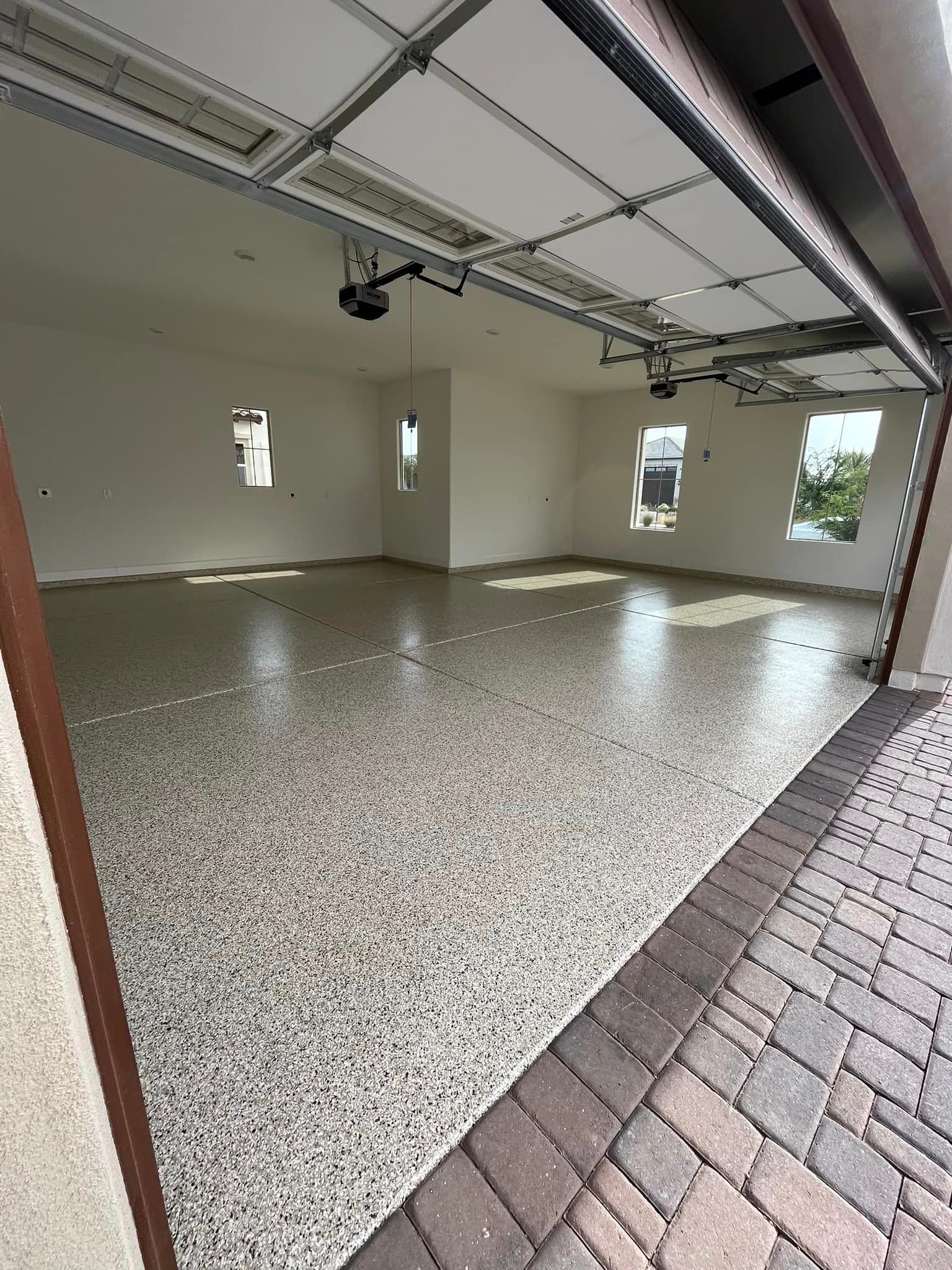 A garage with a garage door open and a brick walkway
