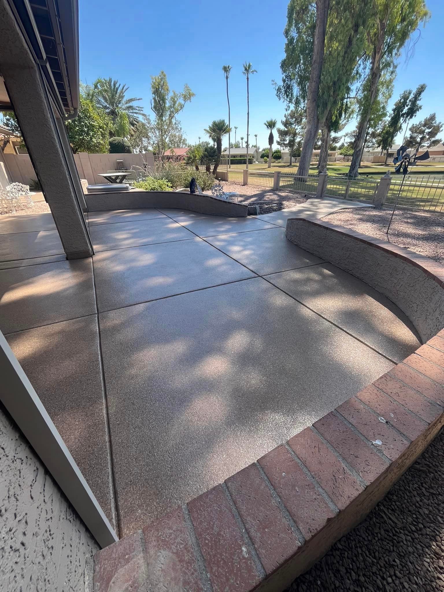 A patio with a brick wall surrounding it and palm trees in the background