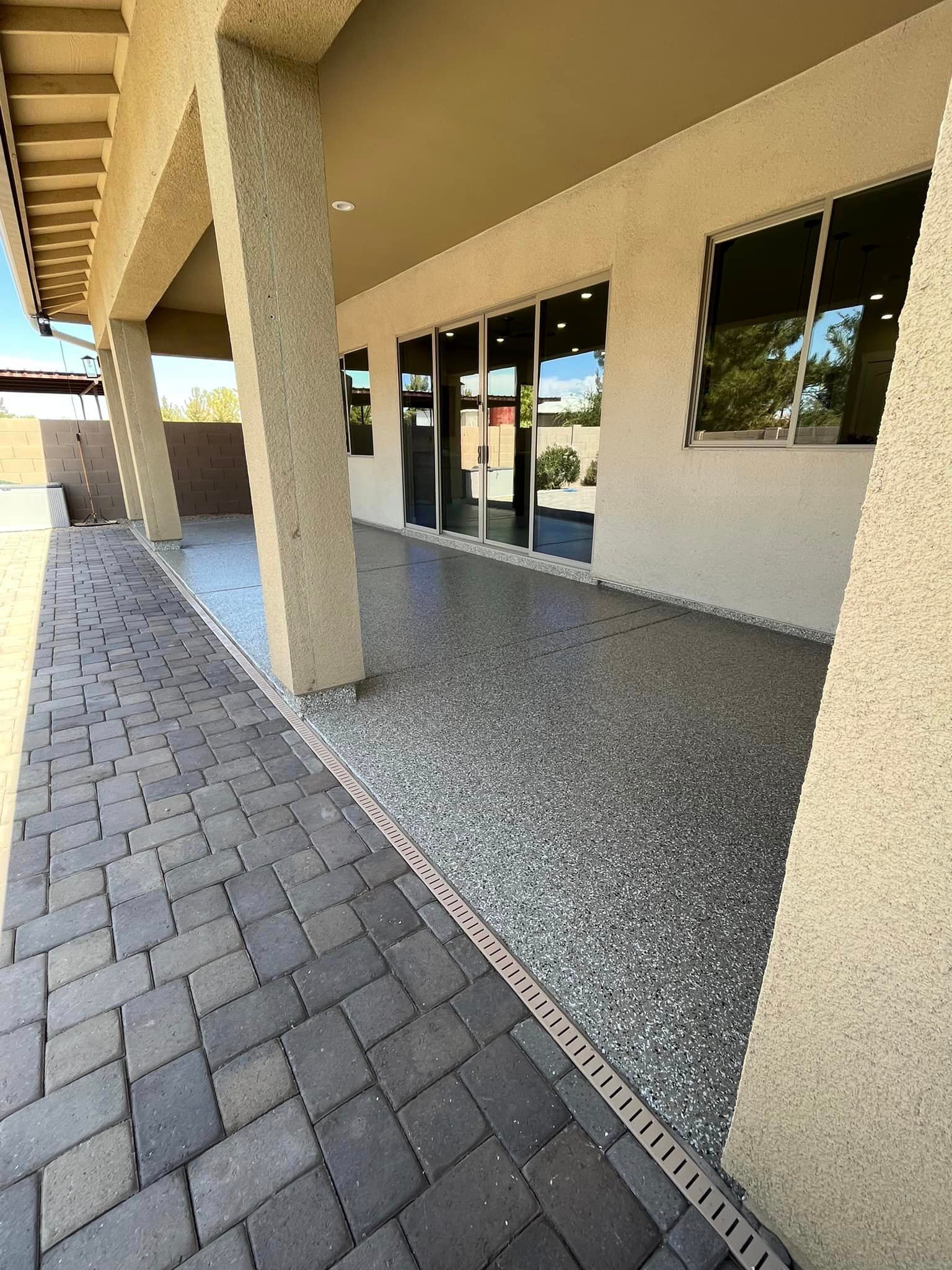 A brick walkway leading to a large building with a concrete floor.