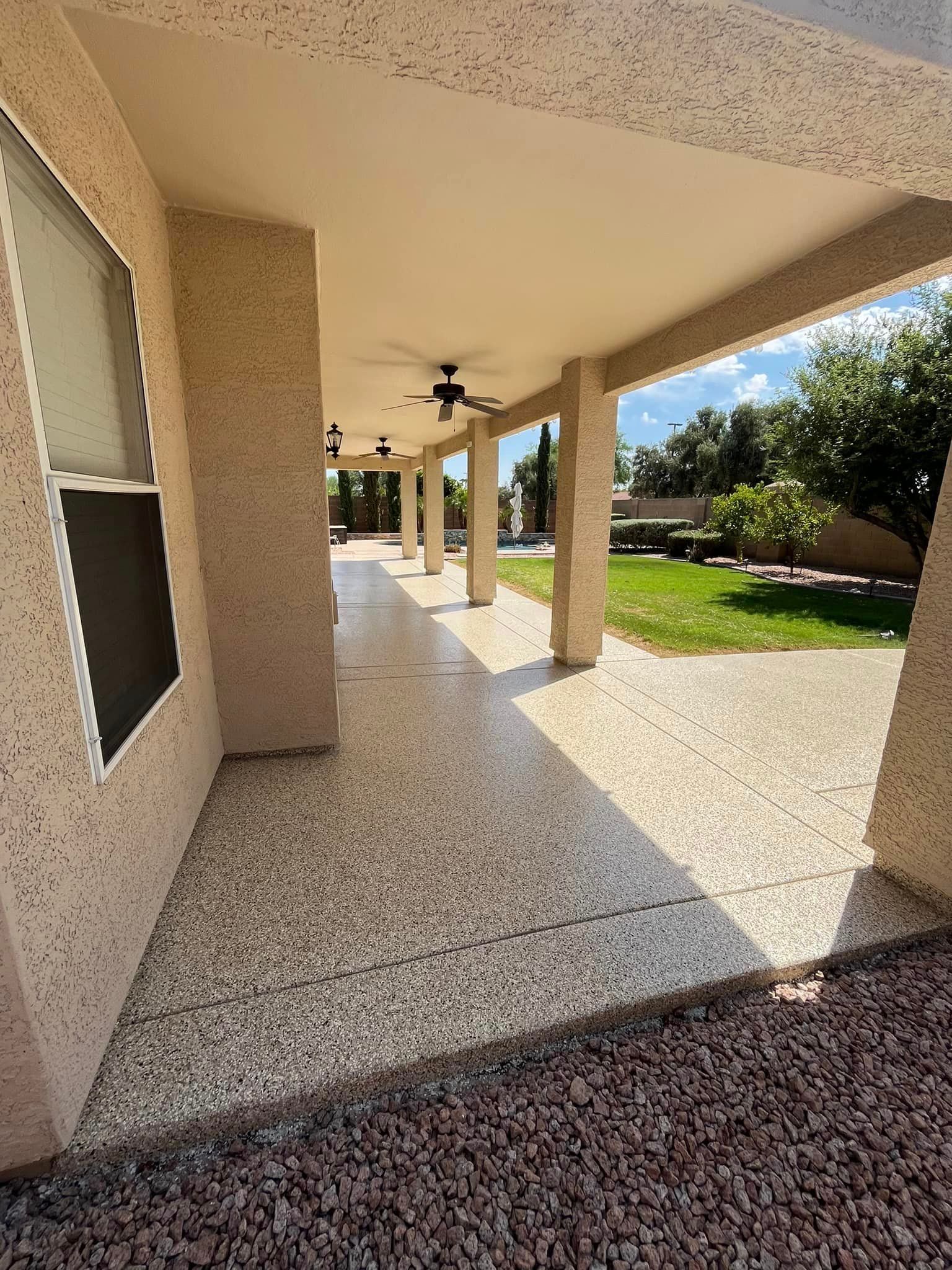 A covered walkway leading to a house with a ceiling fan.