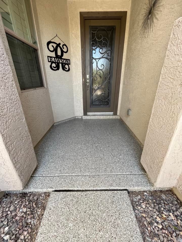 A front porch with a concrete floor and a wrought iron door.