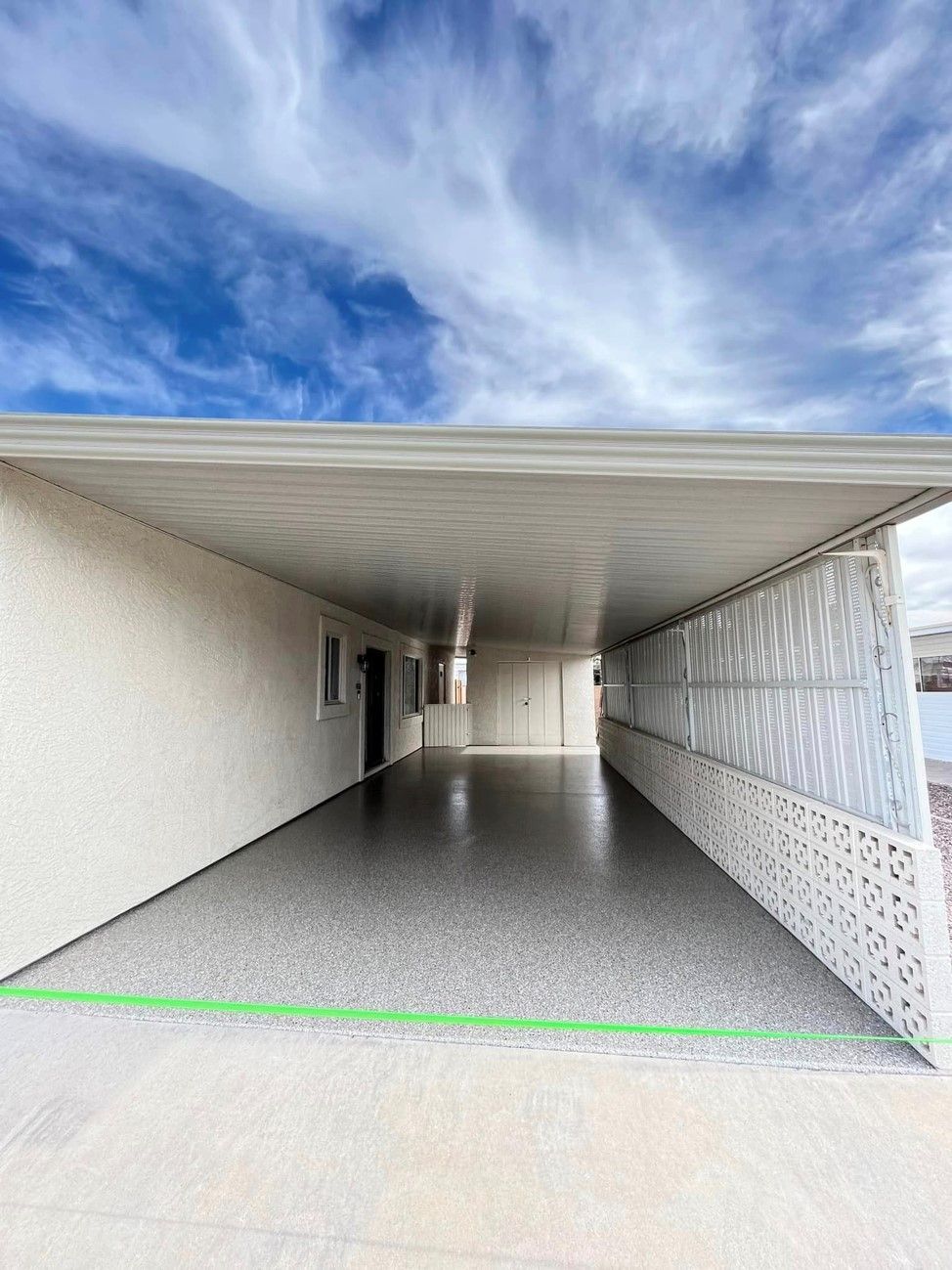A long driveway leading to a house with a blue sky in the background.
